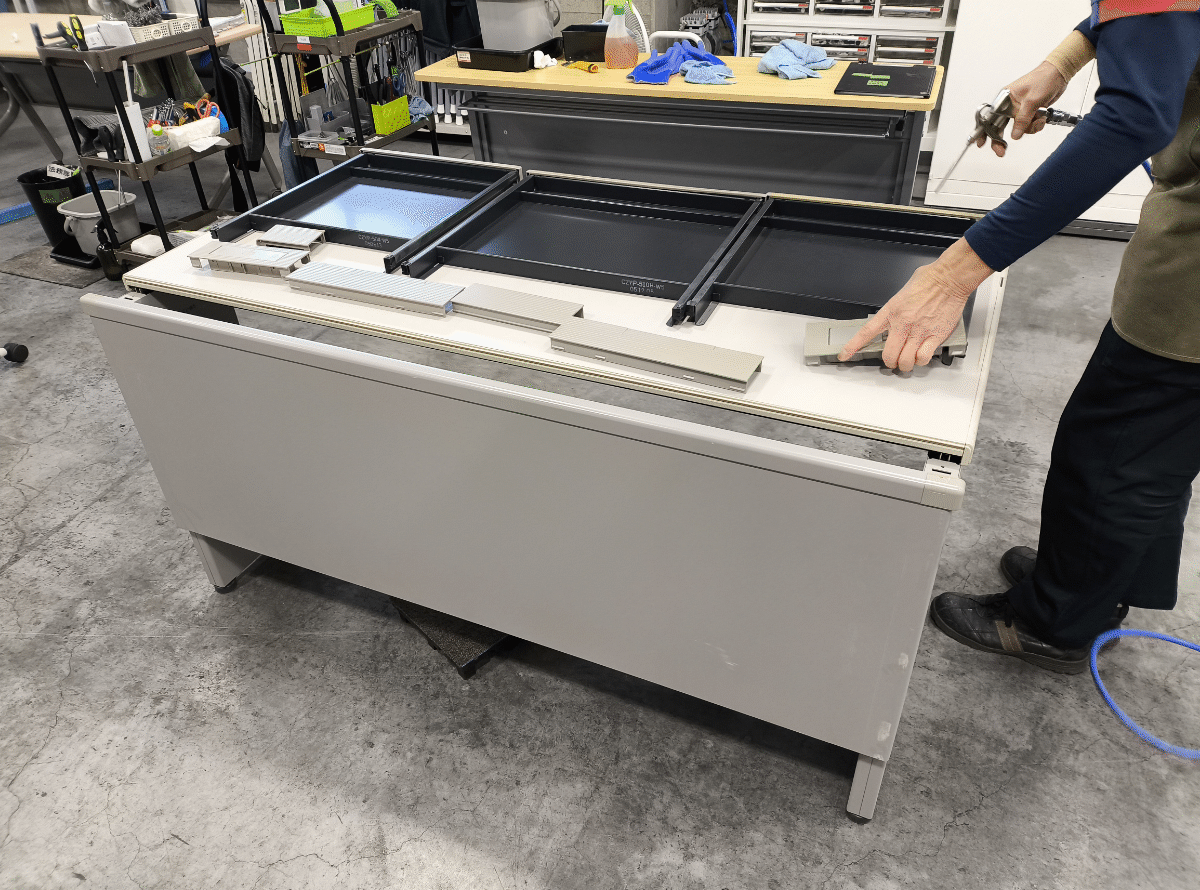 中古デスクの引き出し内部を丁寧に清掃する様子